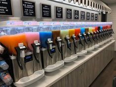 a row of soda machines filled with different colored drinks