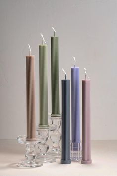 five candles are lined up next to each other in different colors and sizes on a table