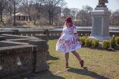 a woman in a white dress is walking near a statue