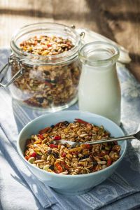 two bowls filled with granola next to a bottle of milk