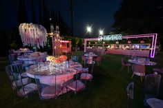 the tables are set up for an event with pink lighting and chandeliers hanging from the ceiling