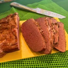 a yellow plate topped with sliced meat next to a knife