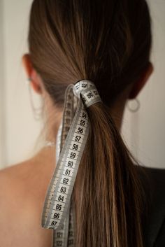 a woman with a measuring tape in her hair is looking at the back of her head