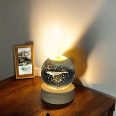 a lamp that is sitting on top of a wooden table next to a framed photo