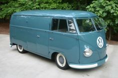 a blue vw bus parked in front of some trees