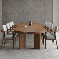 a wooden table surrounded by white chairs in front of a wall with geometric designs on it