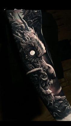 a black and white photo of a man's arm with dragon tattoos on it