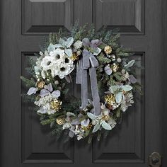 a wreath on the front door with flowers and greenery hanging from it's side