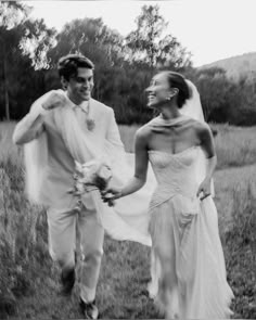 a bride and groom are walking through the grass