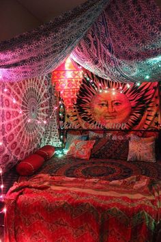 a bed covered in blankets and pillows under a canopy with lights on the headboard