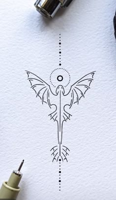 some type of ink drawing on paper with scissors and markers next to it, which has an image of a bird in the middle