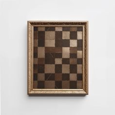 a brown and white checkerboard pattern in a gold frame hanging on a wall