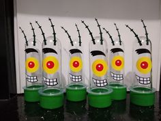 four plastic containers with faces painted on them and barbed wire behind them, sitting on a counter