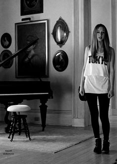 a woman standing in a living room next to a piano