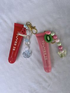 two personalized lip balm tubes are on a white sheet with beaded charms