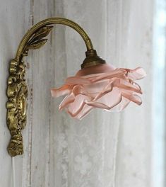 an antique wall light with pink glass shade