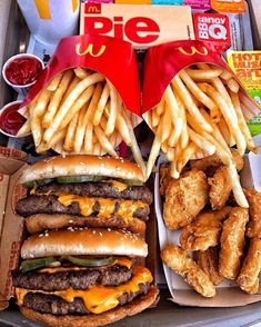 two trays filled with different types of fries and burgers next to each other