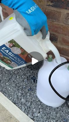 a person in blue gloves is pouring water into a white jug