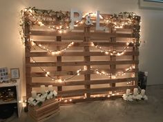 a wooden pallet with candles and flowers on it is decorated with fairy lights, greenery and the word p & l