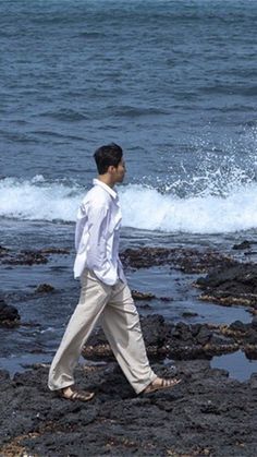 a man is walking on the rocks near the water