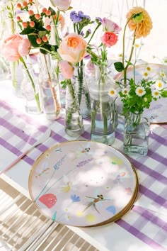 an image of a birthday party with flowers in vases and plates on the table