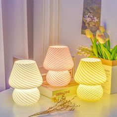 three small lamps sitting on top of a table next to a vase with flowers in it