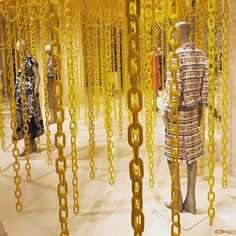 several mannequins with chains hanging from them in a room filled with yellow objects