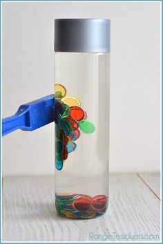 a plastic toothbrush in a glass jar filled with colorful buttons and paperclips