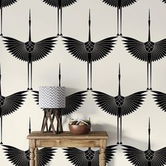 an art deco style wallpaper with black and white feathers on it, next to a lamp