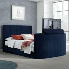 a bed with a blue headboard sitting in a bedroom next to a large window