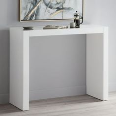 a white console table with a painting on the wall