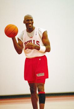 a man holding a basketball in his right hand and wearing red shorts on the other