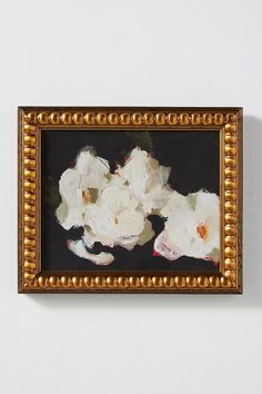 white flowers in a gold frame on a wall