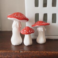 three red and white mushrooms sitting on top of a wooden table next to each other