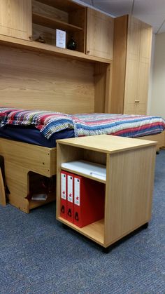 a bed and desk in a room with blue carpeted flooring next to a book shelf