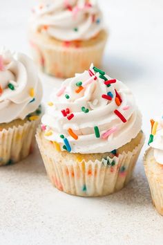 several cupcakes with white frosting and sprinkles