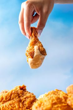 a person is dipping something into some kind of fried food in the air with their fingers