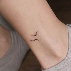 a woman's ankle with a small bird tattoo on her left side ribcage