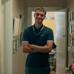 a man is standing in the hallway with his arms crossed and looking at the camera