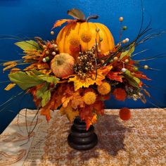 a vase filled with lots of different types of flowers and leaves on top of a table