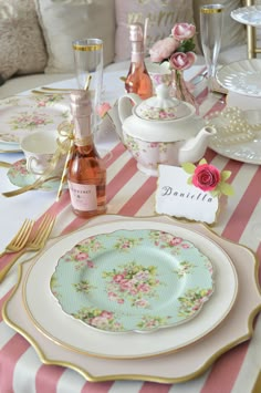 the table is set with pink and white plates, silverware, champagne bottles and flowers