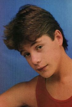 a young man in a red tank top posing for a photo