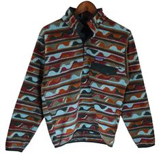 Iconic Retro Patagonia snap-t with awesome tribal aztec pattern in very stylish multi color blue, red and orange. Rock the one that made Patagonia famous in the 80s and 90s. This synchilla is very soft and cozy and feels incredible. You can instantly feel the quality and warmth of this product in hand. Perfect fall and winter jacket especially good on cool days wearing around the house. I love my snap t jackets especially when they are baggy and comfy like this one. Becoming very hard to find si Retro Patagonia, Patagonia Snap T, Aztec Pattern, Pullover Jacket, Patagonia, Casual Wear, Mens Jackets, Ready To Wear, Winter Jackets