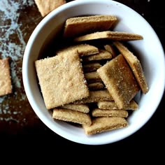 a bowl filled with crackers sitting on top of a table next to other pieces of food