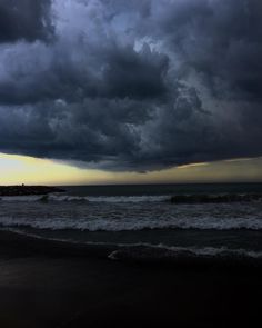 the sky is dark and cloudy over the ocean