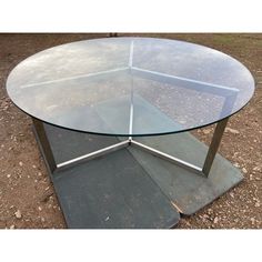 a glass table with metal legs on the ground