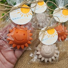 four small orange and white items in plastic bags with twine on them, one being held by someone's hand