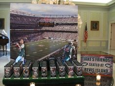 a table topped with boxes and candles next to a large poster on the wall behind it