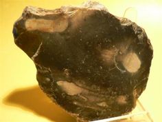 a piece of black rock sitting on top of a yellow table next to a white object