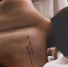 a woman laying in bed with her back turned to the side and writing on it